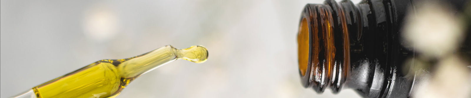 Close-up of a pipette and a jar with CBD oil